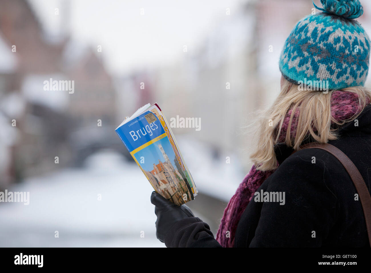 Eine weibliche Touristen ihr Reiseführer nach Brügge mit einem gefrorenen Kanal in der Ferne zu betrachten. Stockfoto