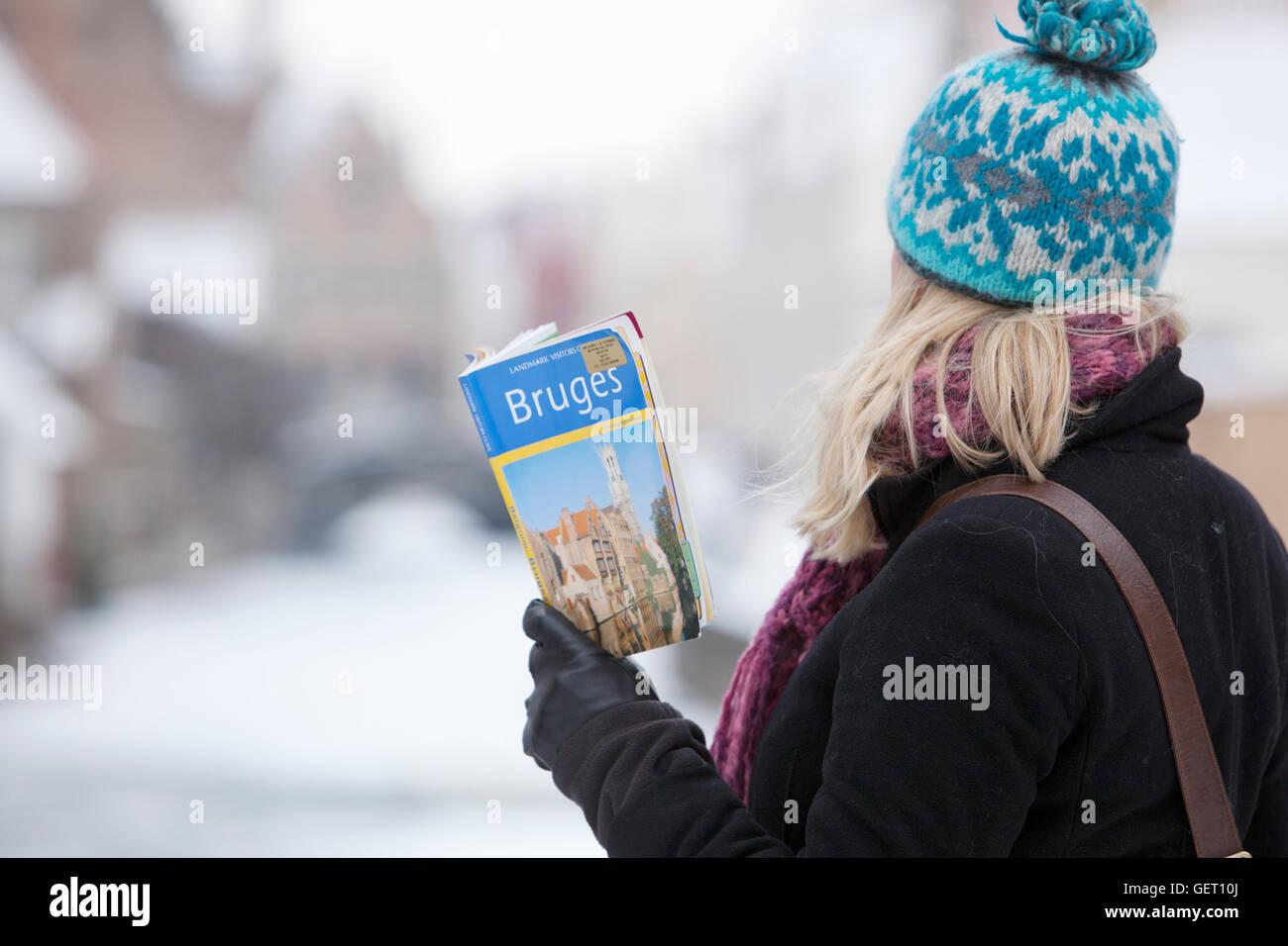 Eine weibliche Touristen ihr Reiseführer nach Brügge mit einem gefrorenen Kanal in der Ferne zu betrachten. Stockfoto
