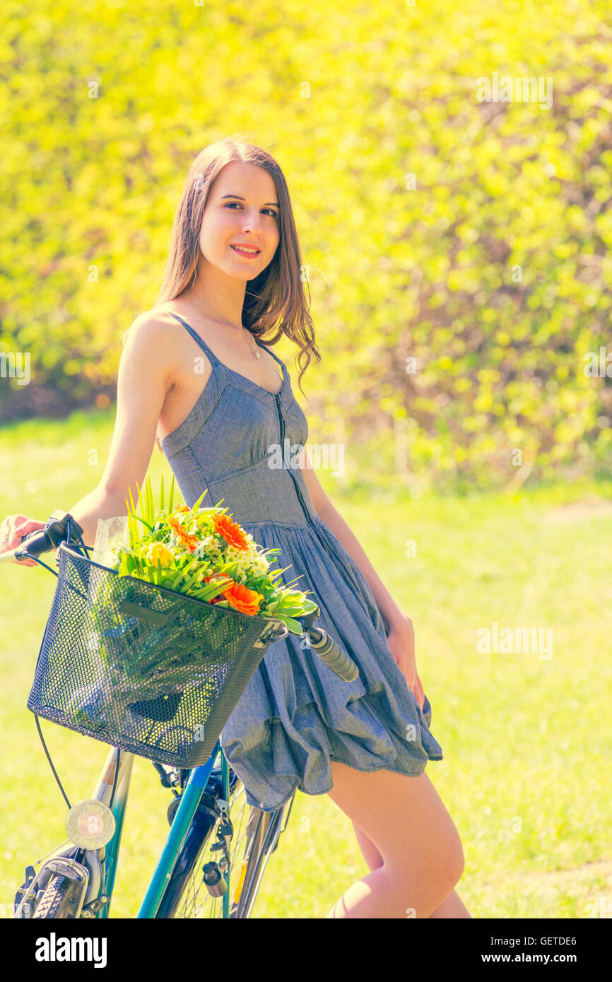 Schöne junge Frau auf Fahrrad mit Blume im park Stockfoto