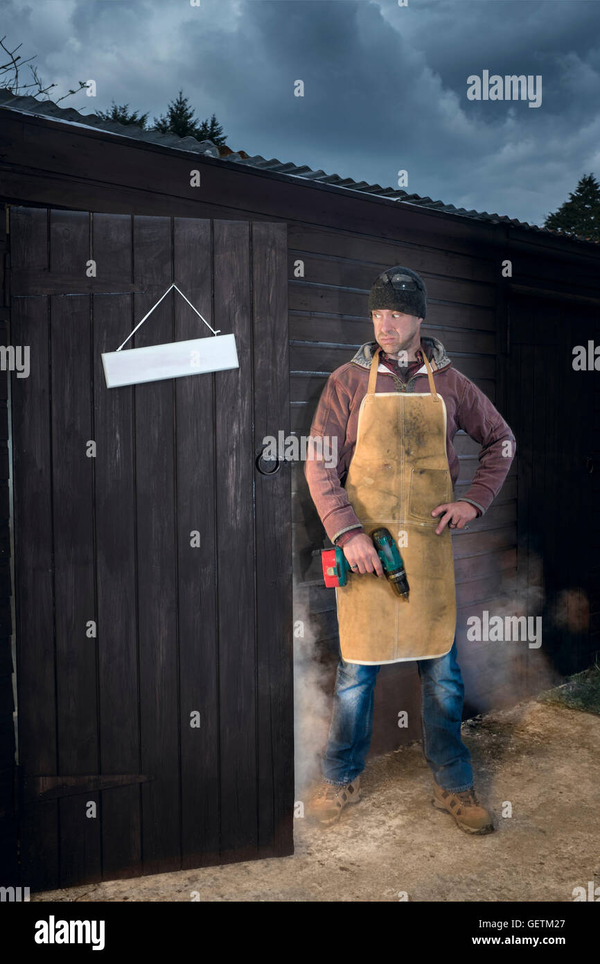 Ein Mann sucht erbittert um den Rauch aus seiner Werkstatt gießen. Stockfoto