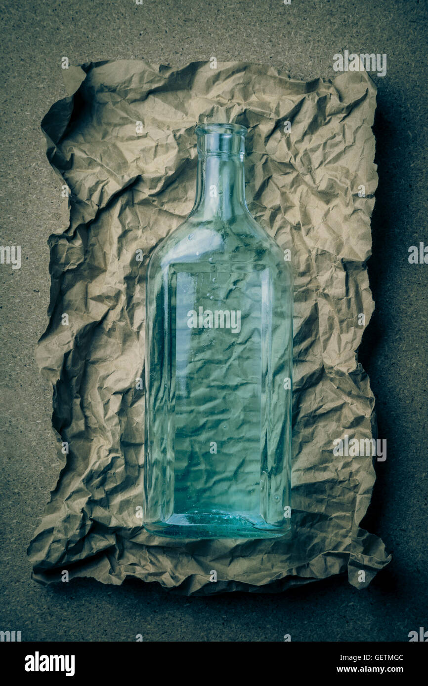 Blaue Glasflasche auf ein zerknittertes Papierhintergrund. Stockfoto