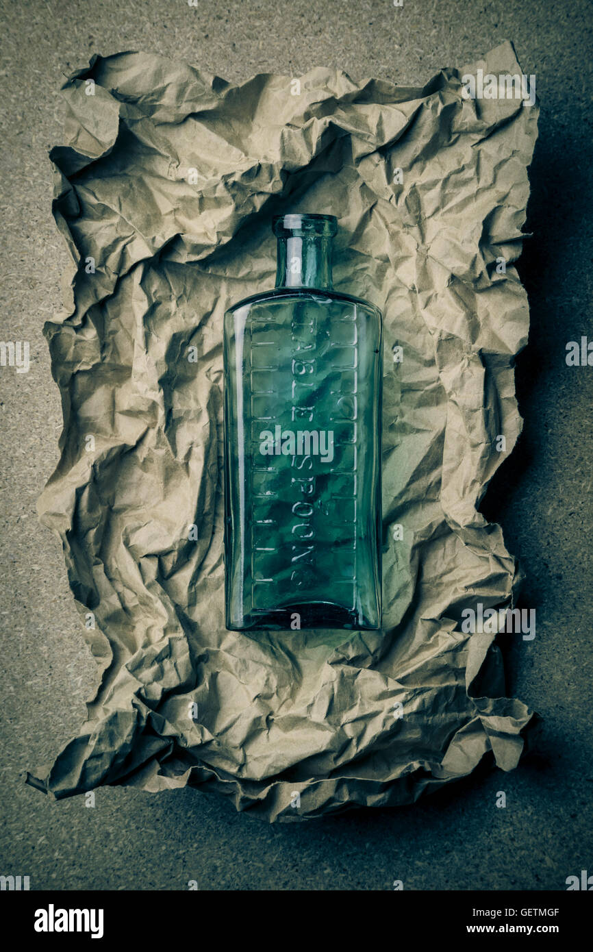 Blaue Glasflasche auf ein zerknittertes Papierhintergrund. Stockfoto