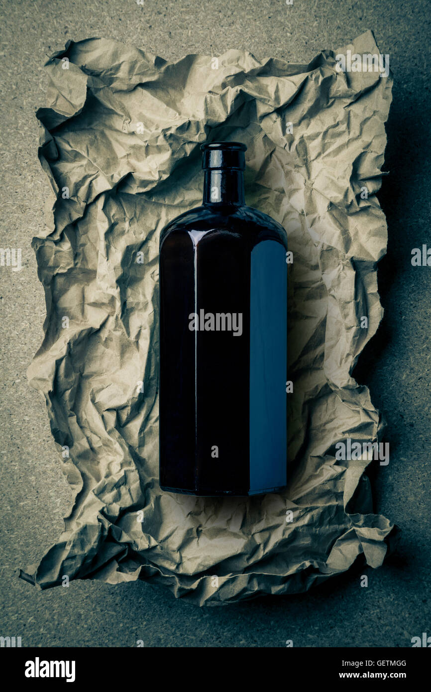 Schwarzglas achteckige Flasche auf ein zerknittertes Papierhintergrund. Stockfoto