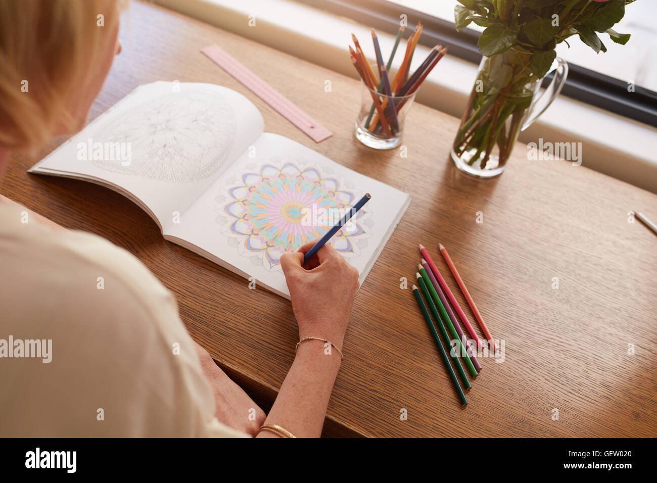 Frau zu Hause entspannen und Zeichnung in Malbuch für Erwachsene. Frau Färbung Entwürfe mit Farbstiften für Entspannung zu Hause Stockfoto