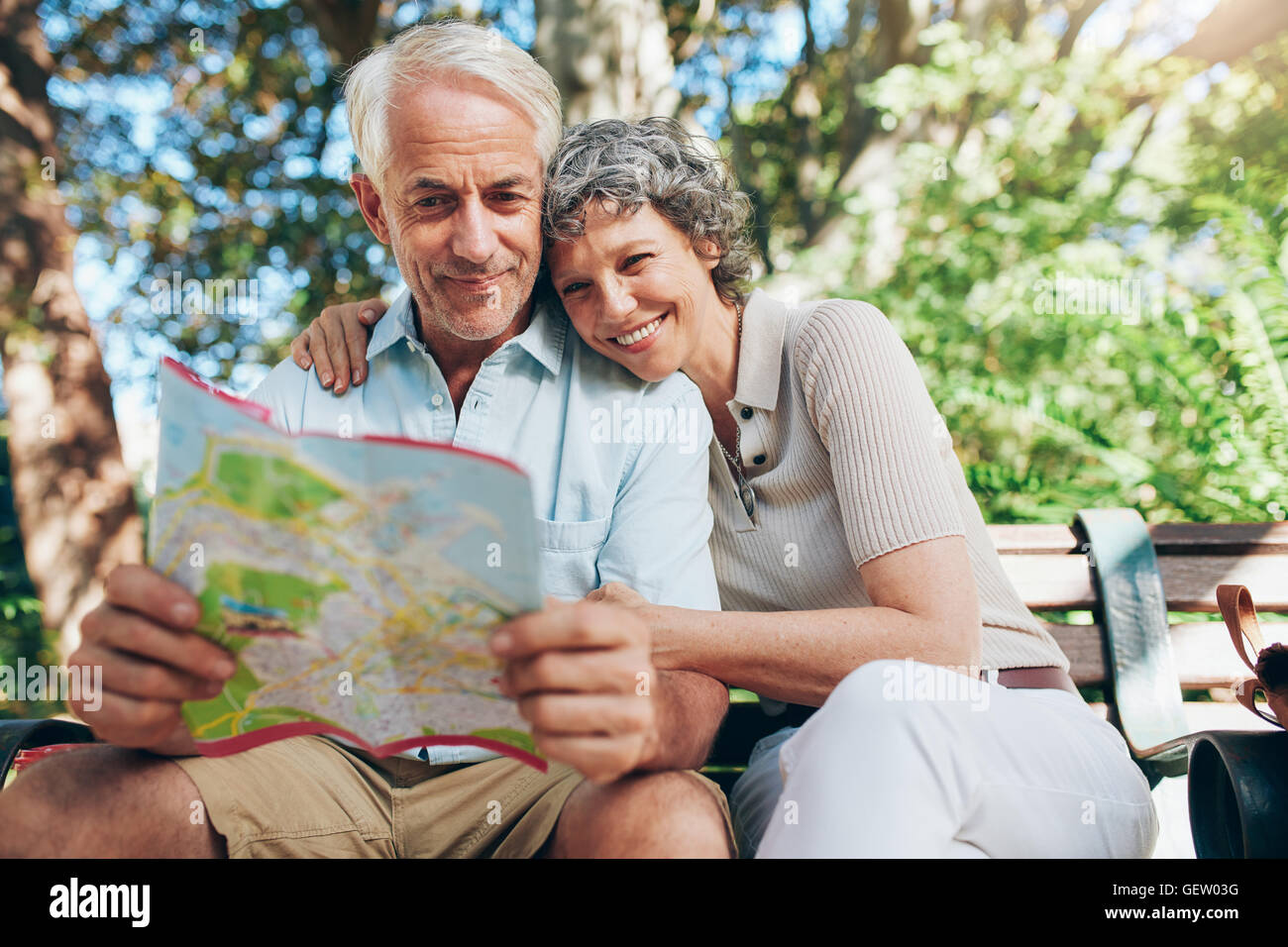 Paar Reifen Touristen im Urlaub. Frau umarmen Mann im Besitz einer Karte. Gerne älteres paar entspannenden Park Bench Lesung Stockfoto