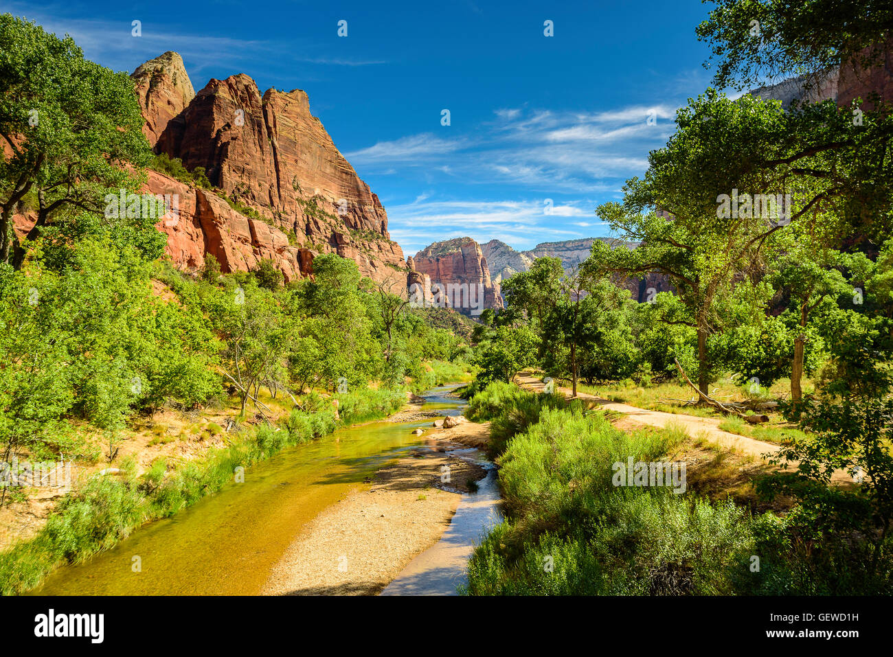 Einem langsam laufenden Fluss in der Mitte Sommer fließt in die Landschaft von grünen Bäumen und orange-roten Sandstein Berge unter blauem Himmel. Stockfoto