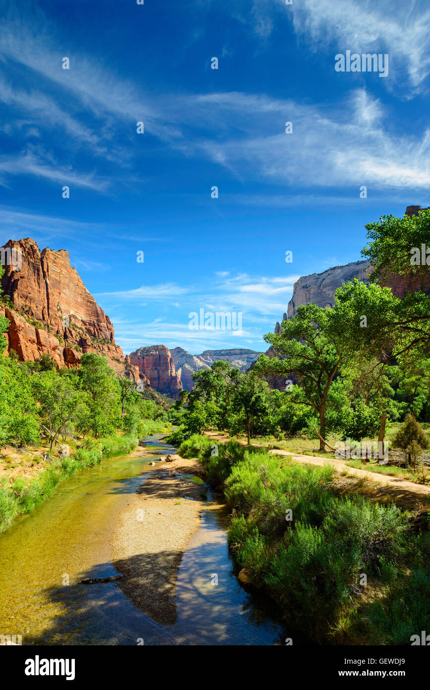 Einem langsam laufenden Fluss in der Mitte Sommer fließt in die Landschaft von grünen Bäumen und orange-roten Sandstein Berge unter blauem Himmel. Stockfoto