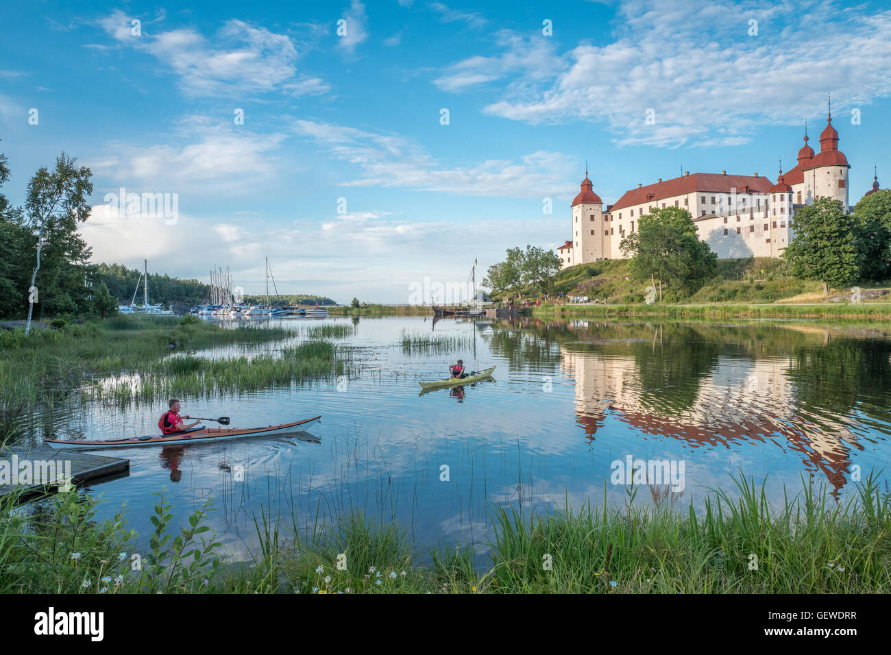 Touristen, die an einem Sommerabend durch See Vanern und Lacko Schloss in Schweden Kajak Stockfoto