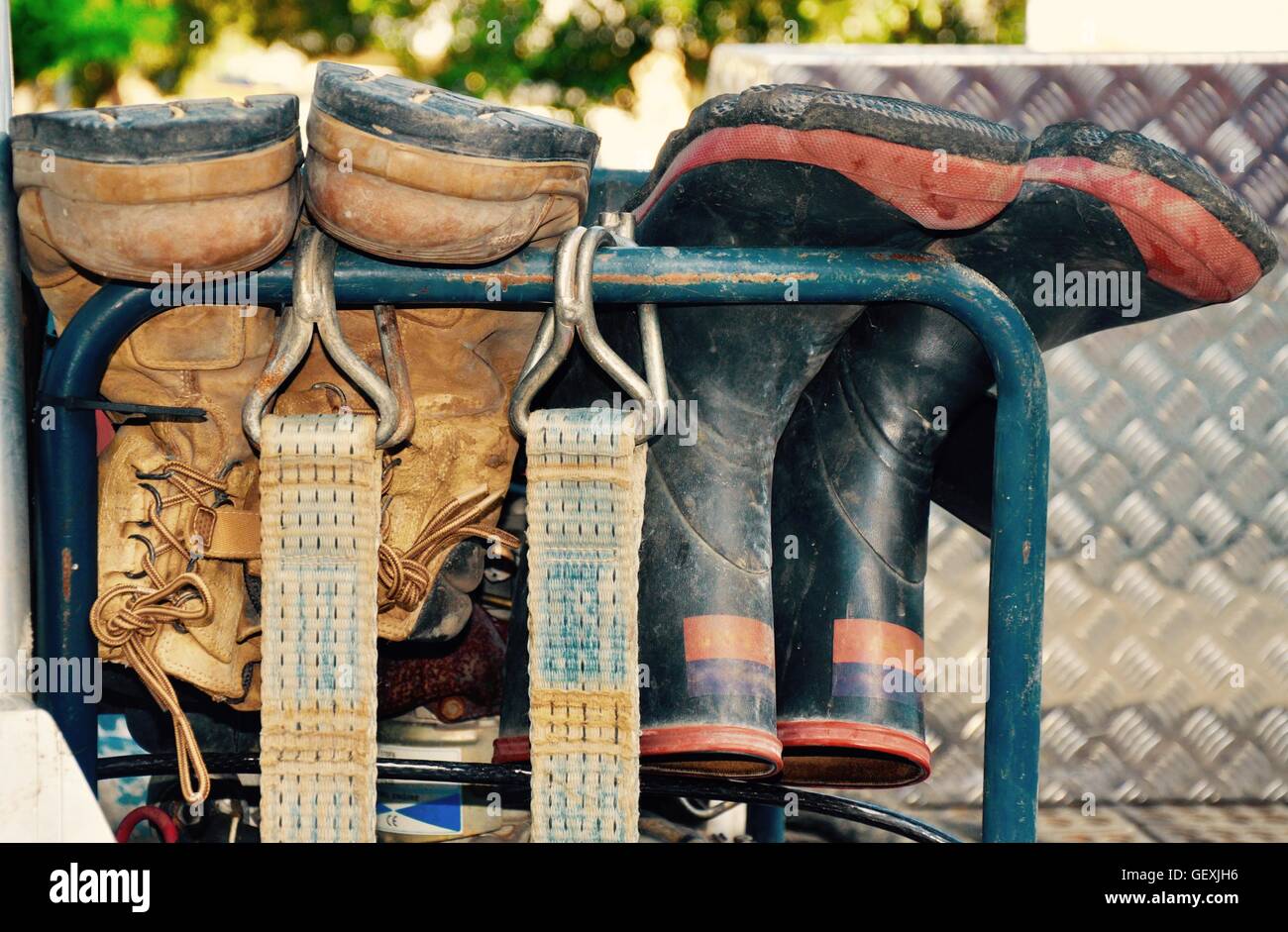 Zwei Paar Stiefel, Stahlkappe Stiefel und Gummistiefel, Metallschiene mit industriellen Riemen hängend arbeitenden Menschen. Stockfoto