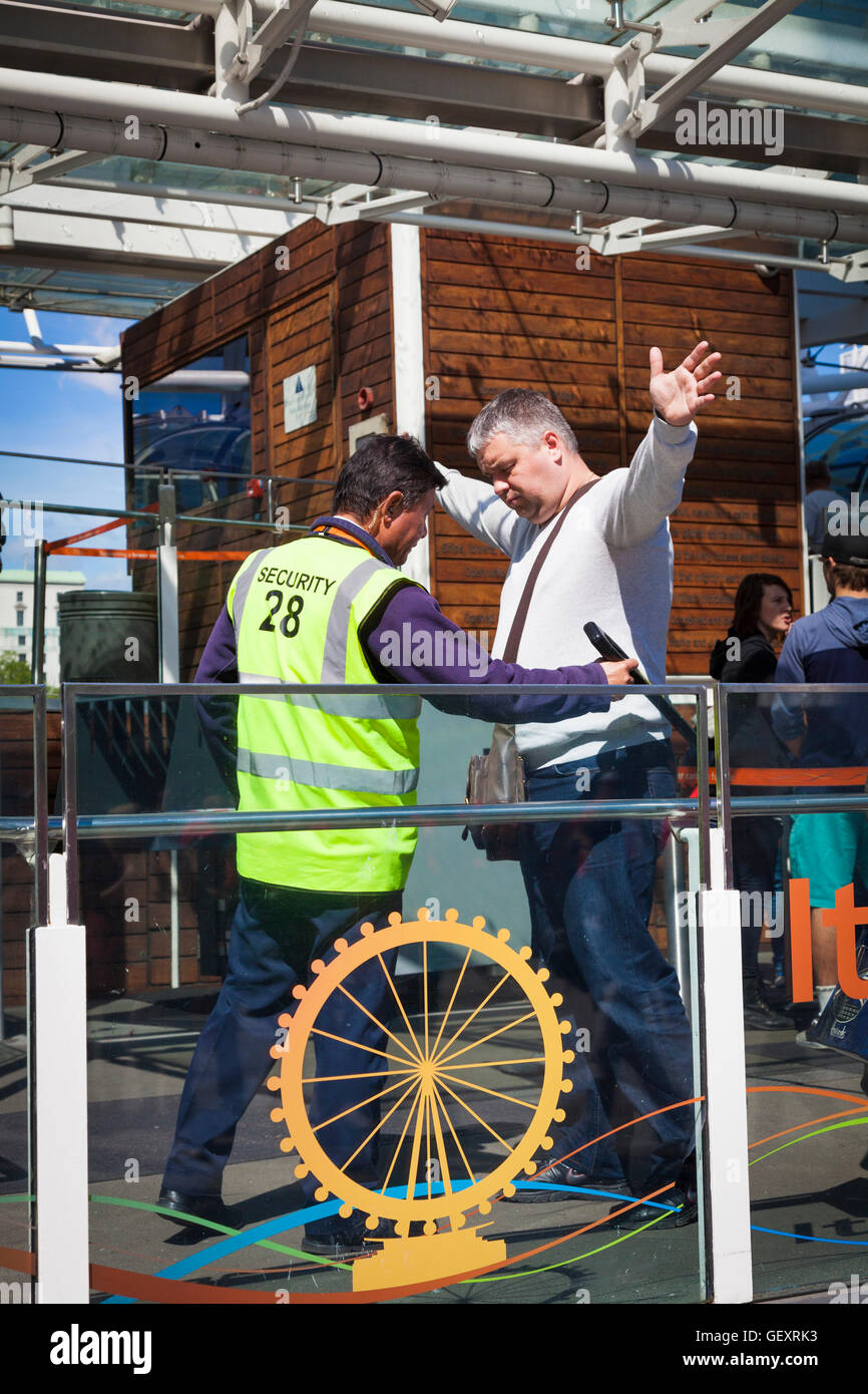 Security Guard Check-Besucher mit Hand statt Metall Scanner vor dem Einsteigen in das London Eye. Stockfoto