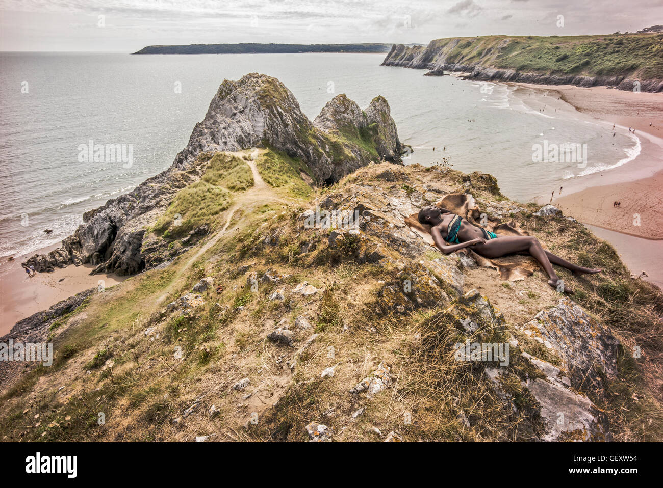 Eine Afro karibische Frau entspannend auf Hügeln mit Blick auf drei Clffs Bucht auf der Gower. Stockfoto