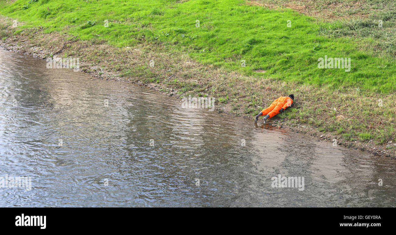 Attrappe eines Mannes mit orangefarbenen Overall am Ufer Flusses während einer Übung des Katastrophenschutzes Stockfoto