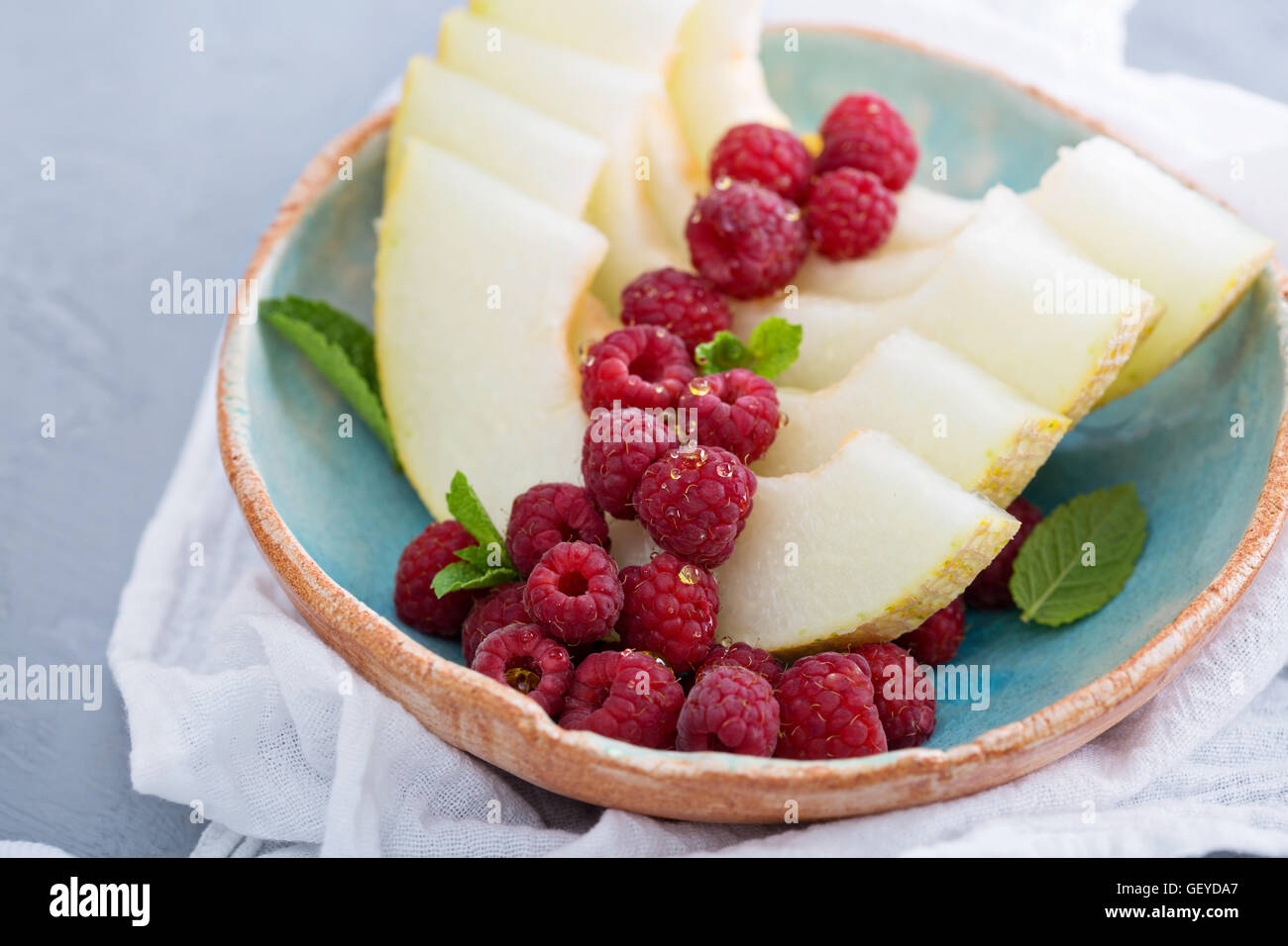 Melonenscheiben mit Himbeeren und Honig serviert Stockfoto