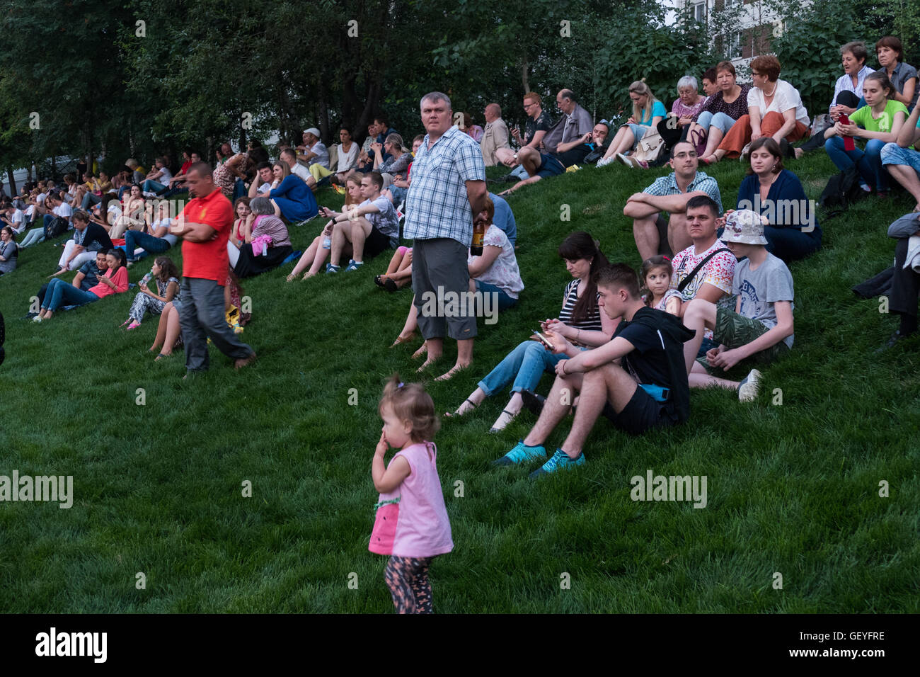 Menschen sitzen auf dem Rasen warten auf das Spektakel Stockfoto