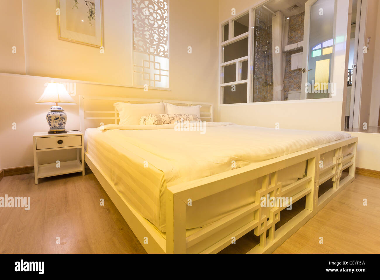 Abstrakte Schlafzimmer in hellen, warmen Farben. großes bequemes Doppelbett im eleganten klassischen Schlafzimmer Stockfoto