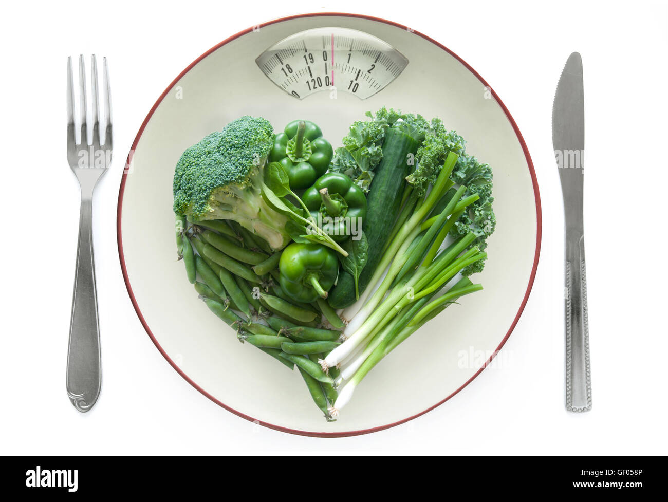 Diät-Konzept, Herz geformt grünes Gemüse auf einem Teller mit wiegen Waage Monitor über einen weißen Hintergrund Stockfoto