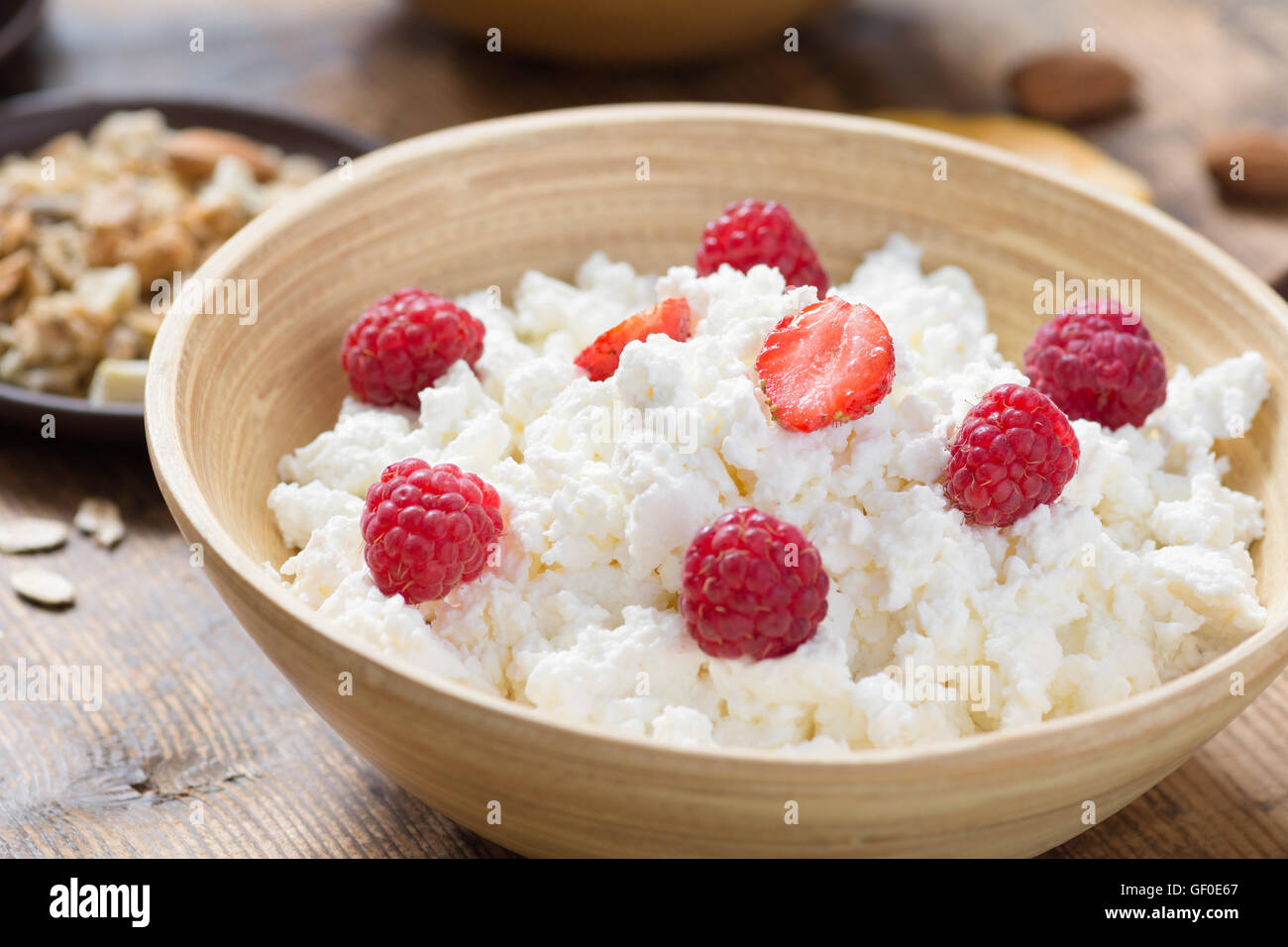Hüttenkäse mit Joghurt, Früchten und Nüssen auf hölzernen Hintergrund, Seitenansicht, selektiven Fokus. Abnehmen, Gesundheit Stockfoto