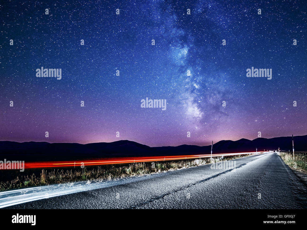 Nachthimmel mit Milchstraße und Sternen. Nacht-Straße mit dem Auto beleuchtet. Lichtspuren Stockfoto