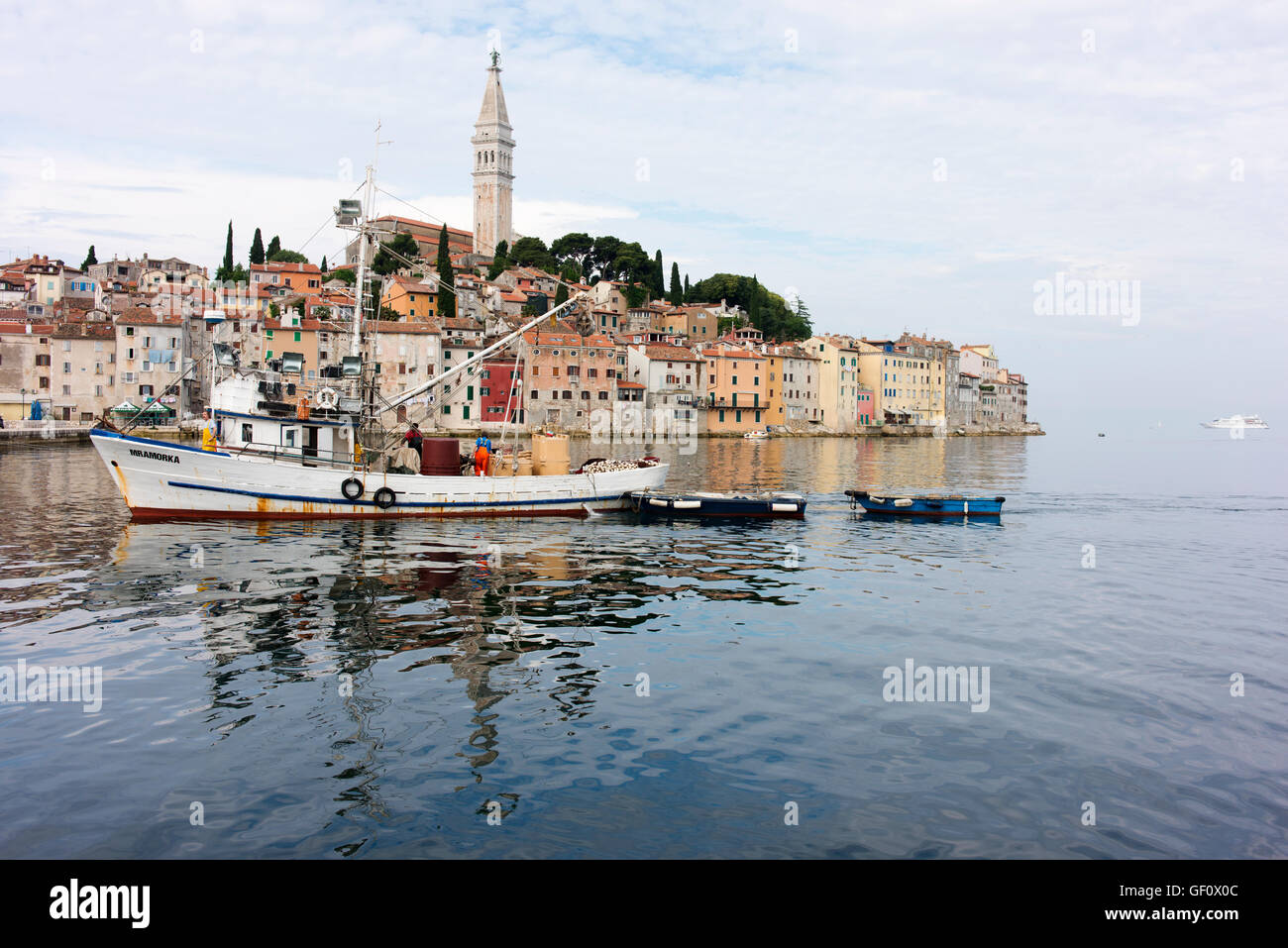 Angelboot/Fischerboot kehrt in den frühen Morgenstunden zum Hafen von Rovinj mit der Altstadt im Hintergrund. Stockfoto