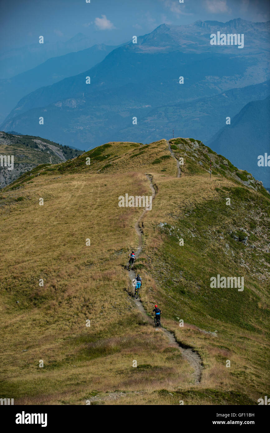 Drei Mountainbiker fahren eine Strecke hoch über den französischen alpinen Ferienort Méribel. Stockfoto