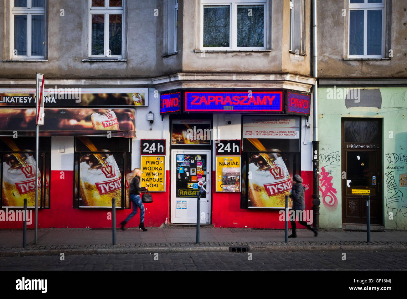 Eine Frau geht über einen 24 stunden off-Lizenz für den Verkauf von Alkohol in Wroclaw, Polen Stockfoto