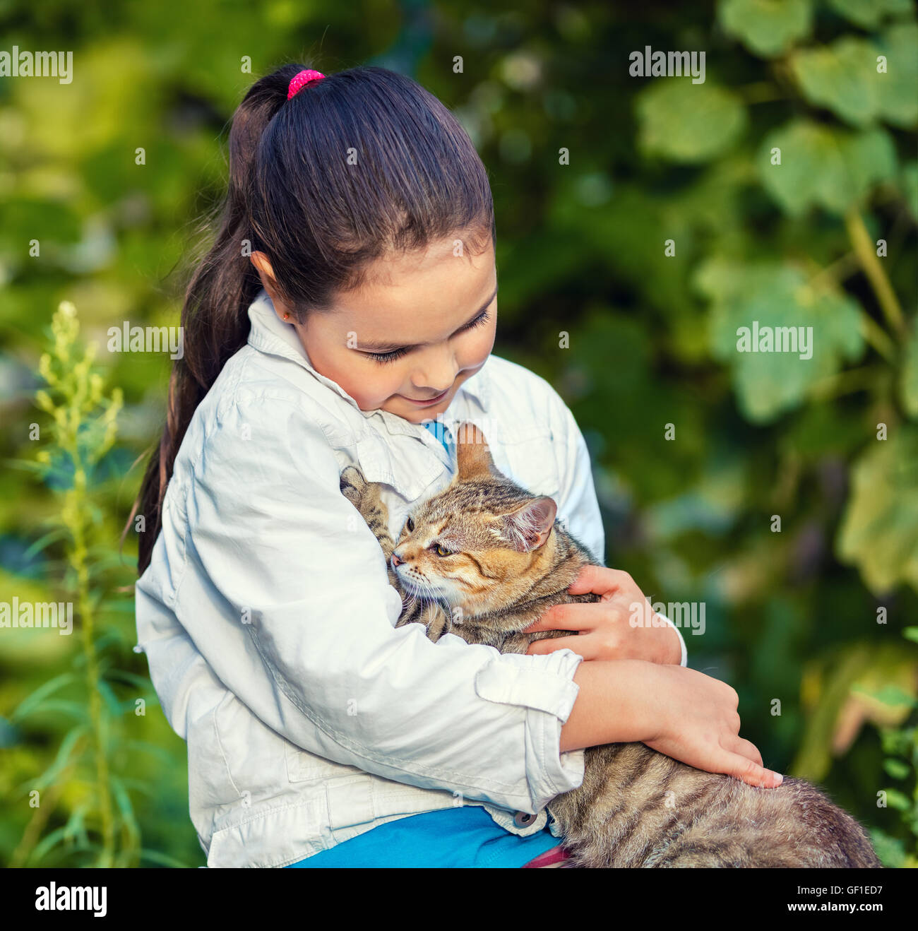 Trauriges kleines Mädchen umarmt eine streunende Katze im park Stockfoto