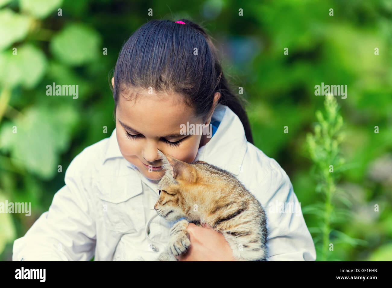Niedliche trauriges Mädchen umarmt eine Katze im Garten Stockfoto