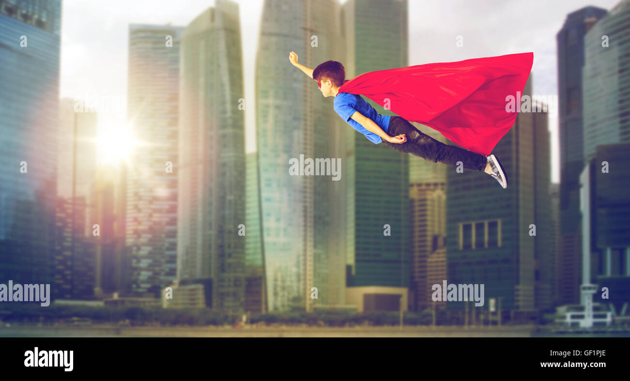 Junge in Superhelden-Cape und Maske fliegt über Stadt Stockfoto