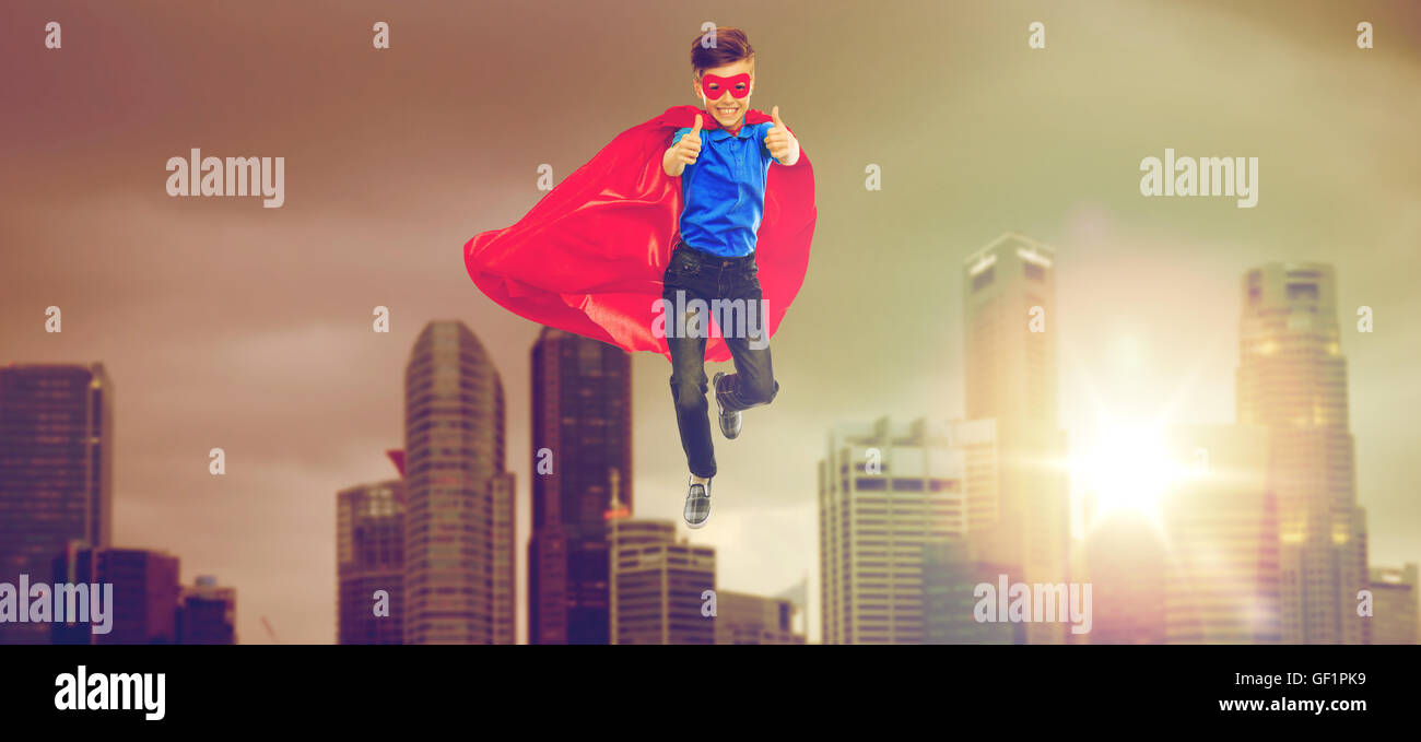 Junge in Superhelden-Cape und Maske zeigt Daumen nach oben Stockfoto
