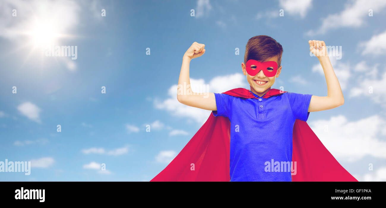 Junge im roten Superhelden Cape und Maske zeigt Fäuste Stockfoto