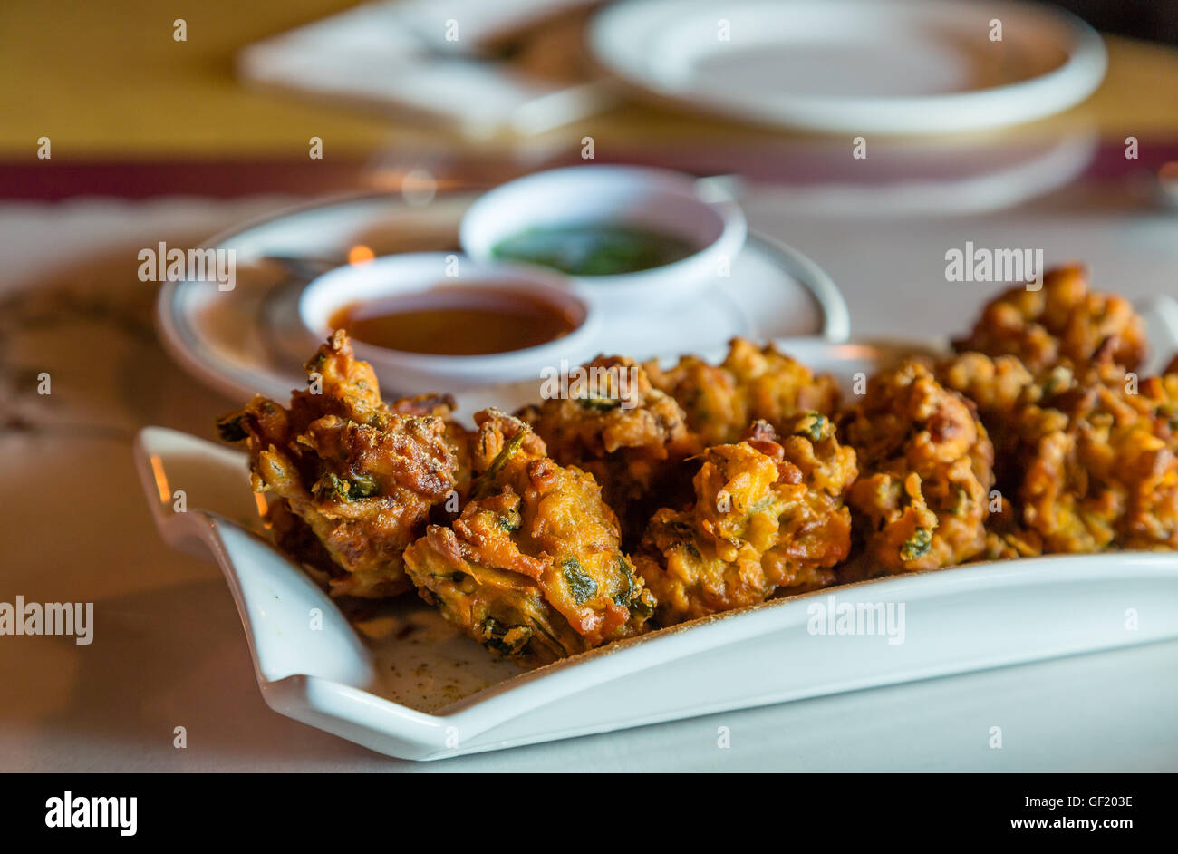 Indische Pakoras in Fensterlicht auf Tisch Stockfoto