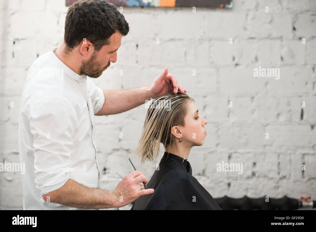 Friseur schneidet Haare mit einer Schere auf Krone schöner zufriedener Kunde in professionellen Coiffeur-salon Stockfoto