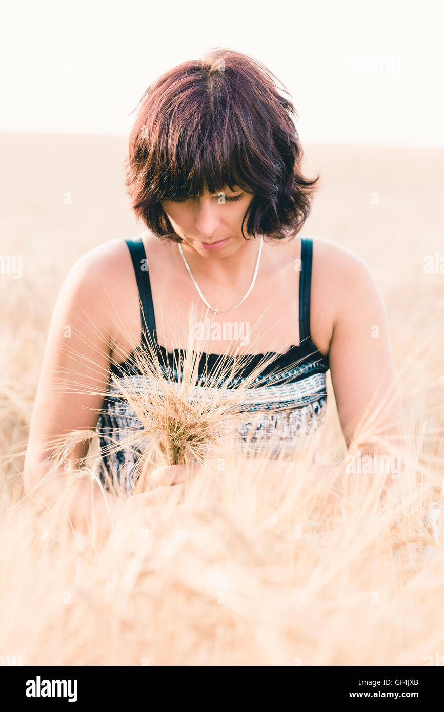 Beauty Woman in einem Sommerkleid ohne Make-up entspannende Landschaft reißen in Blumenstrauß goldene Gerste mit ihr applying Stockfoto