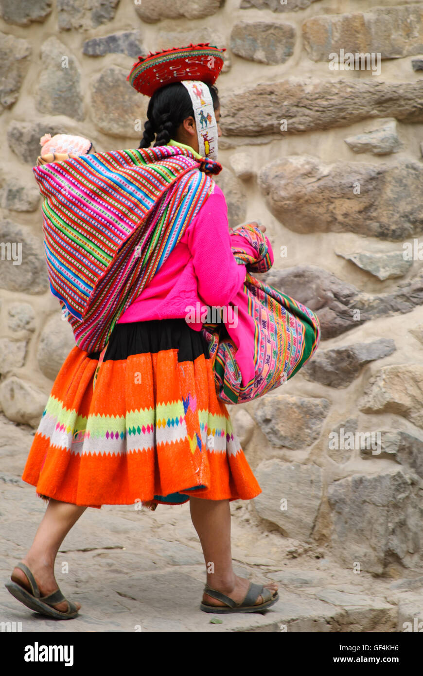 Eine Anden indische Frau in Tracht, die ein Baby auf dem Rücken tragen Stockfoto