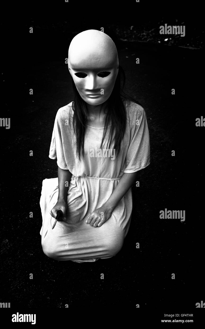 Dunkle Lehre, geheimnisvolle Frau trägt weiße Maske, beängstigend Hintergrund für Bucheinband Stockfoto