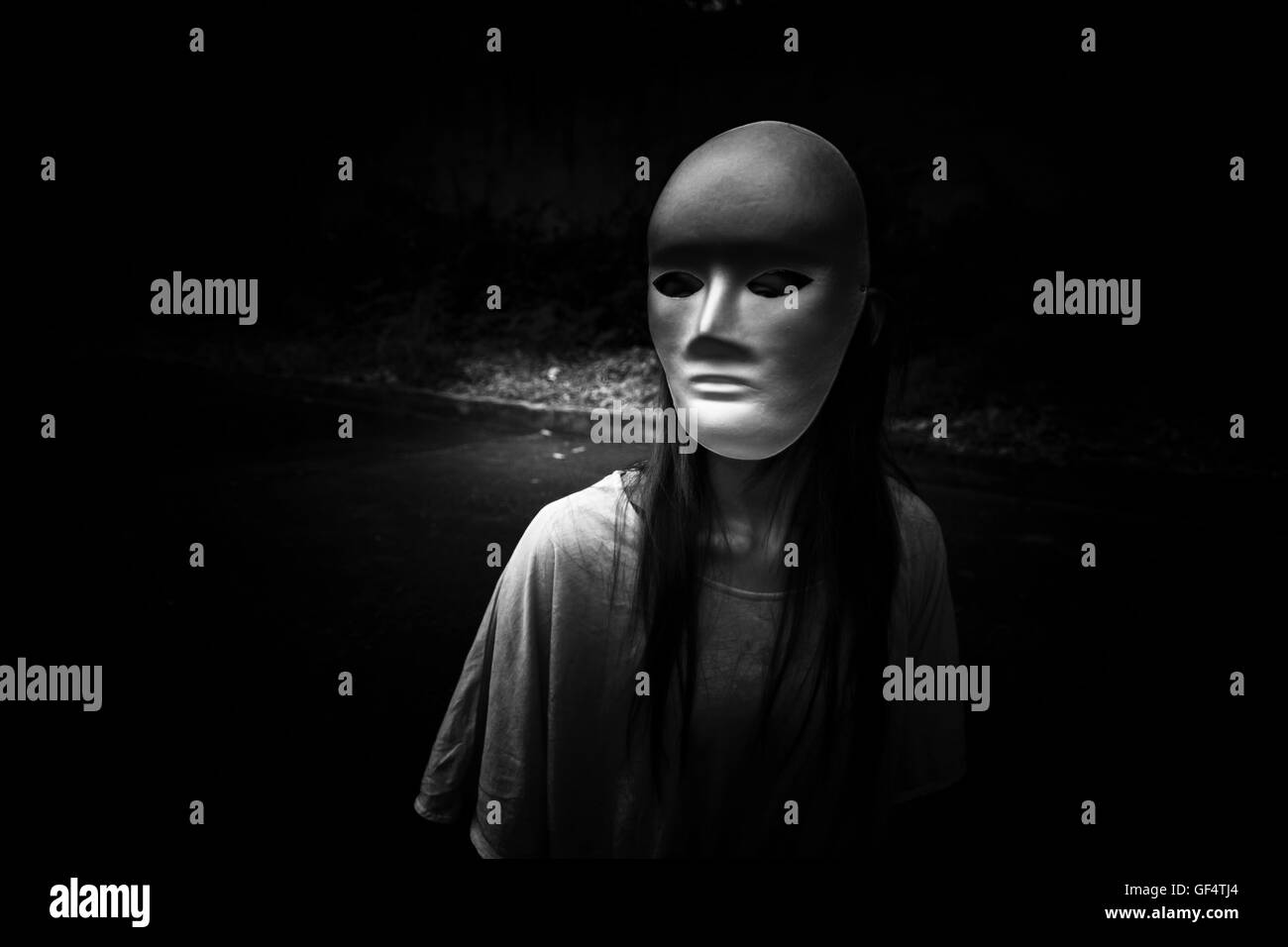 Geheimnisvolle Frau in schwarzem Kleid weiße Maske, beängstigend Hintergrund für Bucheinband Stockfoto