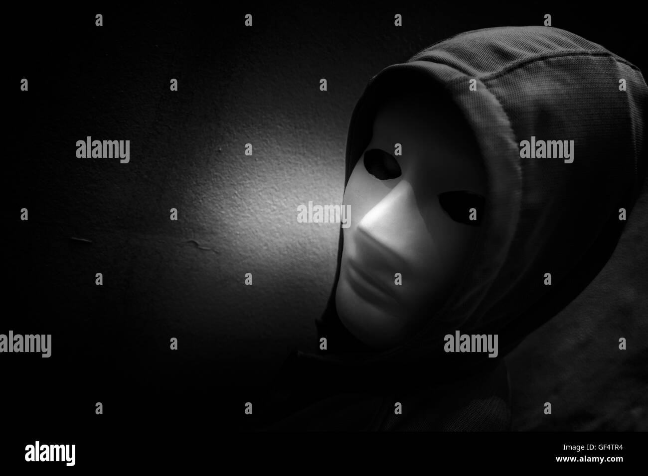 Dunkle Lehre, geheimnisvolle Frau trägt weiße Maske unter Hoodie, beängstigend Hintergrund für Bucheinband Stockfoto