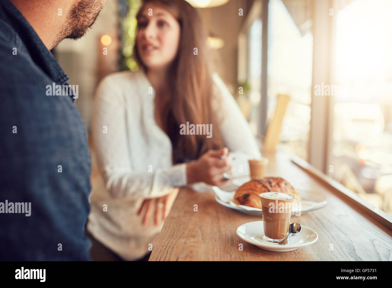 Tasse Kaffee und Essen am Tisch mit paar reden im Hintergrund im Café. Stockfoto