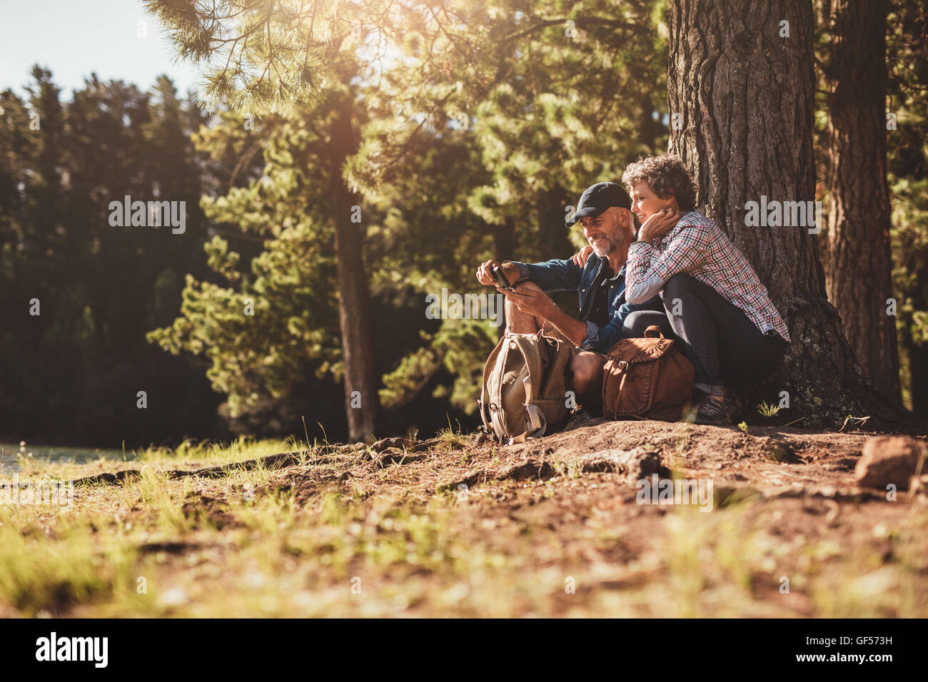 Älteres Paar auf der Suche nach dem Weg mit Hilfe eines Kompasses lächelnd. Älteres Paar im Wald wandern. Stockfoto