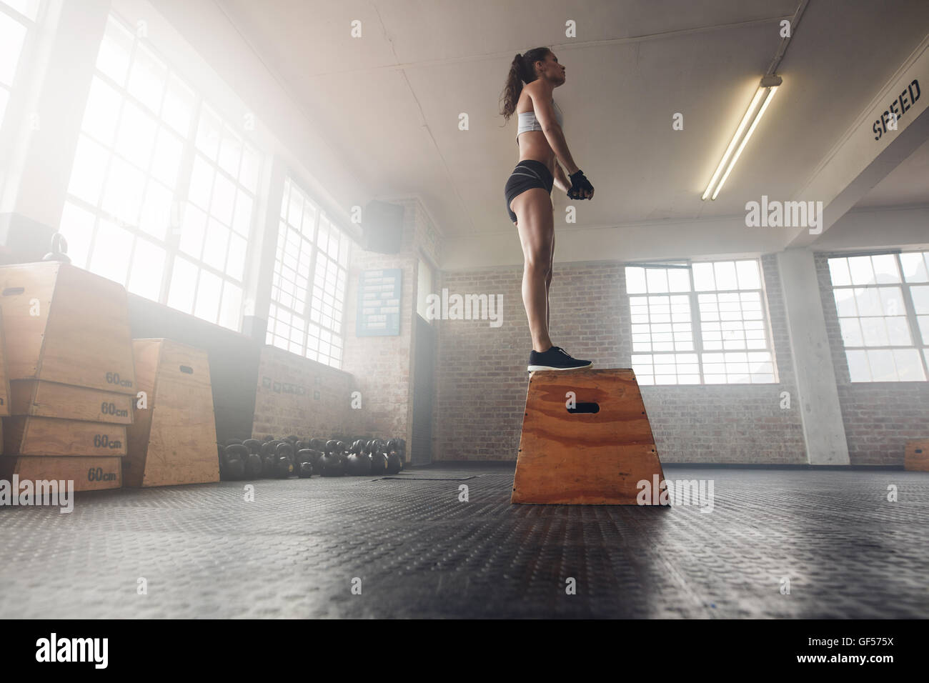 Niedrigen Winkel geschossen Fit junge weibliche Modells in Sportbekleidung steht auf einem Feld am Gym. Muskulöse Frau Feld springen Sport im Fitness-Studio. Stockfoto