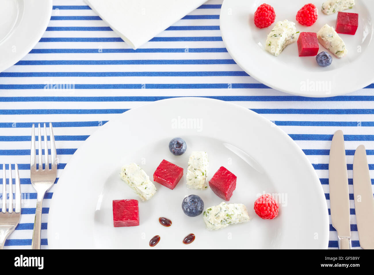 Vorspeise, gemacht von Rüben, Quark mit Früchten auf weißen Platten. Stockfoto