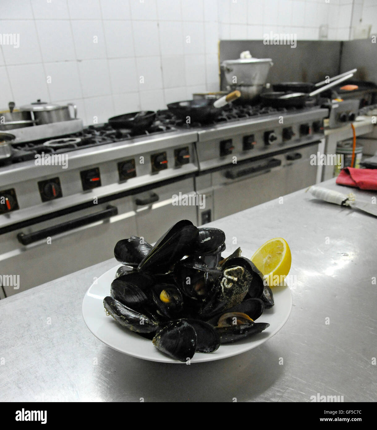 Teller mit frisch gekochten Muscheln auf Sideboard in Restaurantküche Stockfoto