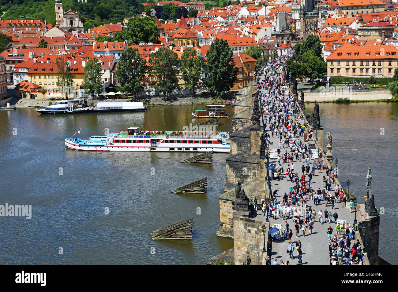 Touristen, die zu Fuß über die Karlsbrücke über die Moldau mit einem Boot Sailig unter ihm in Prag, Tschechische Republik Stockfoto
