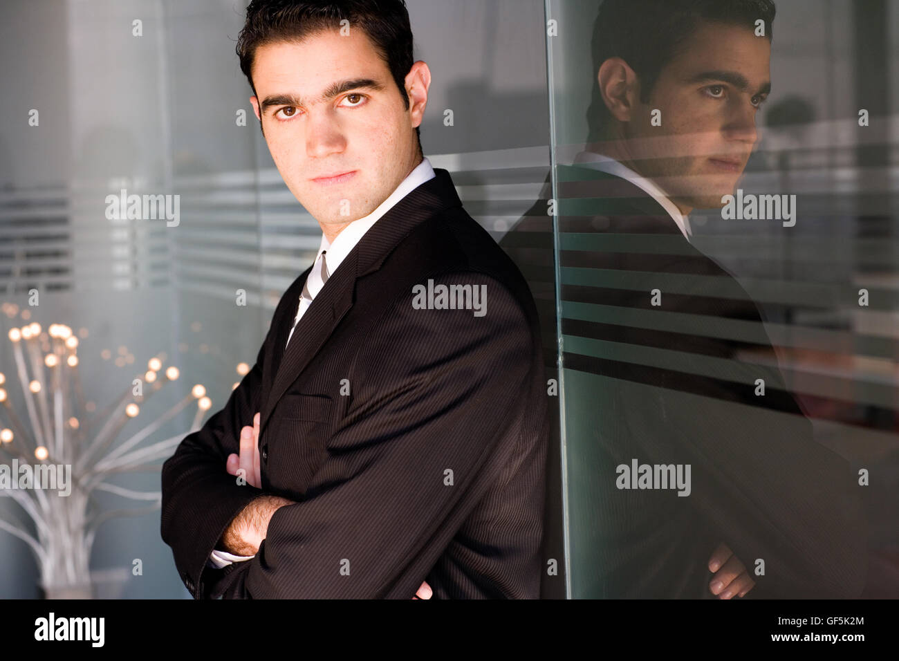 Profil eines Geschäftsmannes und seiner Reflexion über eine Glaswand. Stockfoto