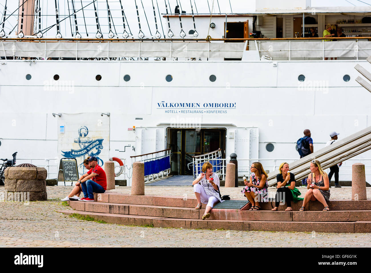 Göteborg, Schweden - Juli 25. 2016: Frauen sitzen auf ein Denkmal aus Stein Treppe sprechen und essen Eis. Eingang zu einer sailboa Stockfoto