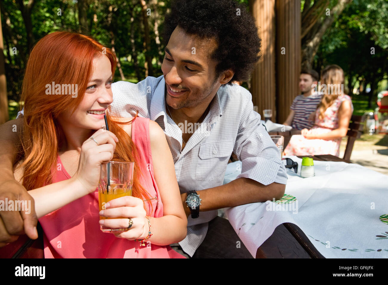 Junges Paar sitzt im Café mit Menschen im Hintergrund. Stockfoto