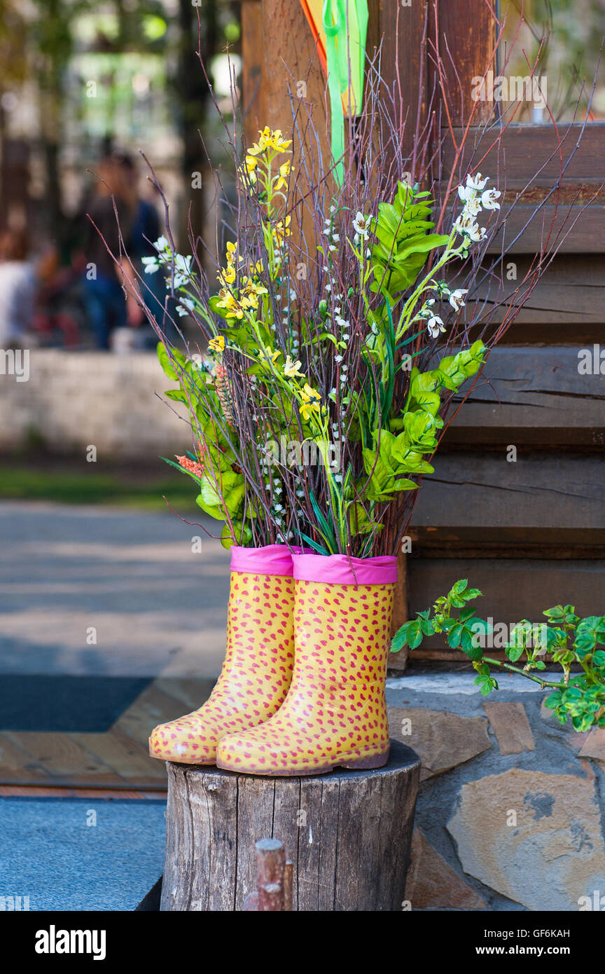 Dekorative Blumenstrauß in Stiefeln auf hölzernen Hintergrund Stockfoto