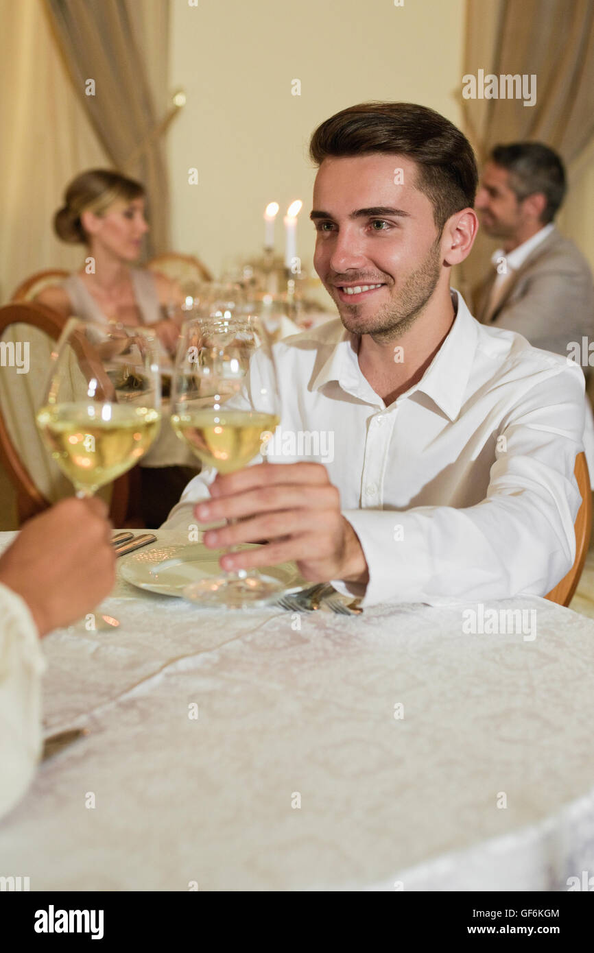 Mann Toasten Glas im Restaurant mit Menschen im Hintergrund. Stockfoto
