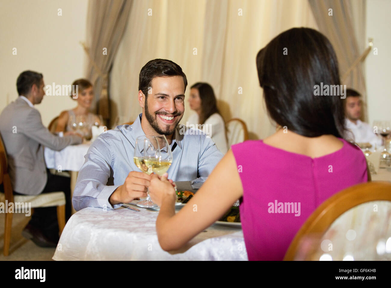 Paar im Restaurant mit Menschen im Hintergrund sitzt. Stockfoto