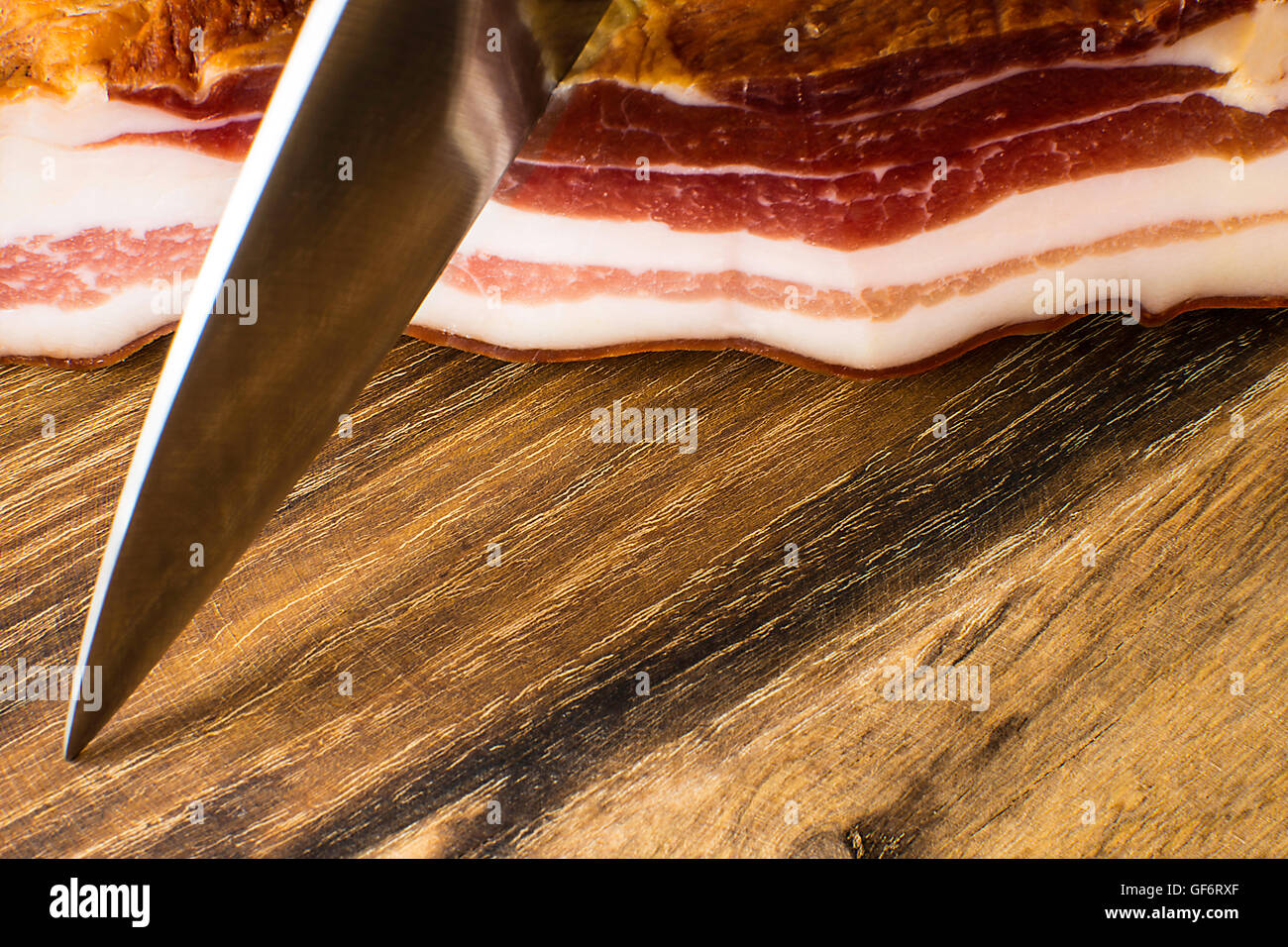 Geräucherter Speck auf Vintage Holzbrett mit einem Messer Schnitt Stockfoto